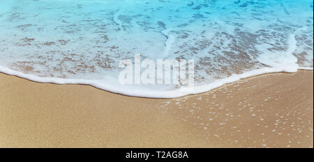 Schäumende Welle an einem Sandstrand Stockfoto