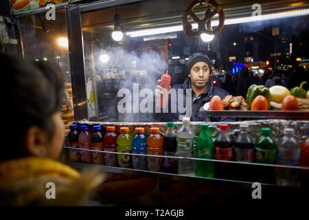 Asiatische Einwanderer New York Manhattan street Hersteller Verkauf von seinem Hot Dog cart Stockfoto