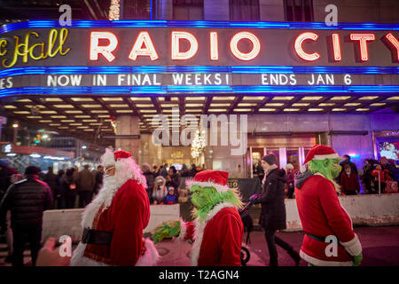 Weihnachtsschmuck Radio City Gaukler verkleidet als Weihnachtsmann und der Grinch auf der Suche nach Tipps, 6. Avenue, Manhattan, New York bei Nacht Stockfoto