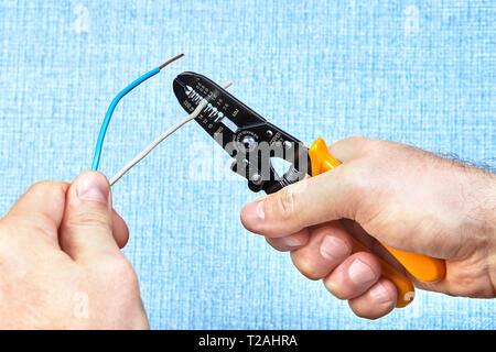 Elektrische Installation arbeiten, mit einem Abisolierer, Elektriker schneidet in Kabel Isolierung ohne Schneiden der Draht-, Kabel Isolierung entfernt wird. Stockfoto