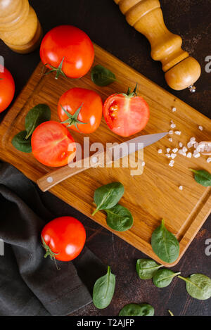 Tomaten, Basilikum und Salz auf hölzernen Schneidebrett Stockfoto