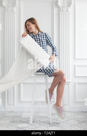 Frau sitzt auf der Hocker entrollt Fabric Stockfoto
