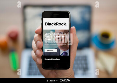 Ein Mann schaut auf seinem iPhone die zeigt die BlackRock Logo (nur redaktionelle Nutzung). Stockfoto