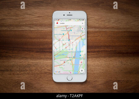 Ein iPhone mit Google Maps Website beruht auf einem einfachen Holztisch (nur redaktionelle Nutzung). Stockfoto