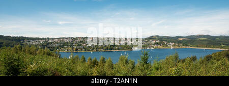 Weiten Blick auf den Sorpesee mit Segelbooten und den Damm mit Langscheid im Hintergrund vor wolkigem Himmel in Sundern, Sauerland, Deutschland Stockfoto