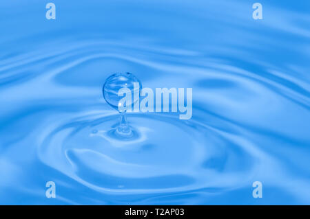 Hellblau gefärbte Wasser Tropfen Splash und Kräuselungen. Makroaufnahme Stockfoto