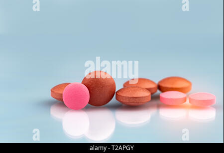 Selektiver Fokus auf orange und pink, runde Tabletten mit Schatten auf farbverlauf Hintergrund. Pharmazeutische Industrie. Apotheke Produkte. Vitamine und suppleme Stockfoto