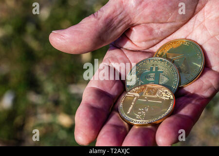 Physische Symbol cryptocurrencies. Golden Bitcoins, des Astraleums und litecoin in Palm der Männer von der Hand. Blockchain Konzept Stockfoto