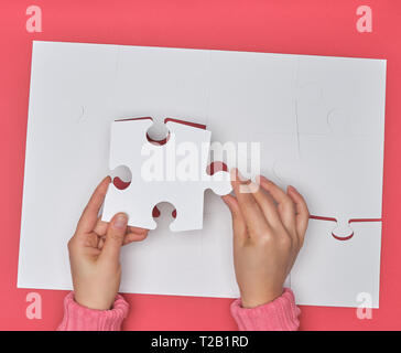 Weibliche Hand weiß große Rätsel auf einem rosa Hintergrund, ein Element fehlt, Ansicht von oben Stockfoto