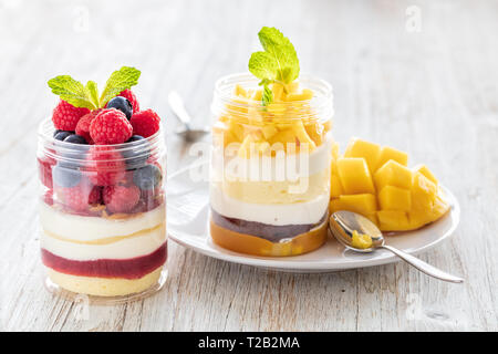 Himbeer und Mango Nachtisch, Käsekuchen, Kleinigkeit, Maus in einem Glas auf einem hellen Hintergrund Stockfoto