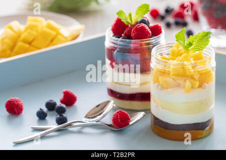 Himbeer und Mango Nachtisch, Käsekuchen, Kleinigkeit, Maus in einem Glas auf einem hellen Hintergrund Stockfoto