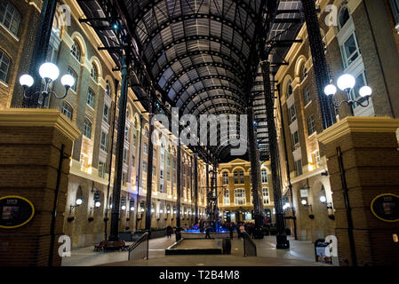 LONDON, UK, 22. MÄRZ 2019: Touristen, die das Heu Galleria in der Nacht. Im 19. Jahrhundert, die Wharf war einer der wichtigsten Punkte der Fo Stockfoto