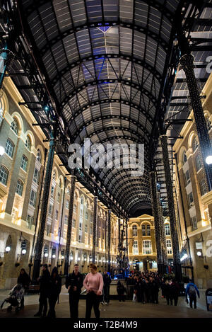 LONDON, UK, 22. MÄRZ 2019: Touristen, die das Heu Galleria in der Nacht. Im 19. Jahrhundert, die Wharf war einer der wichtigsten Punkte der Fo Stockfoto