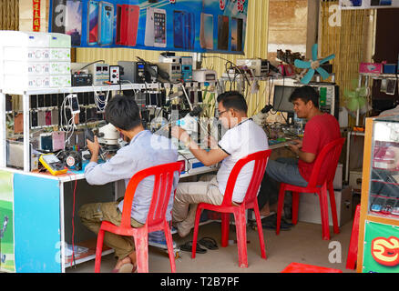 Techniker Reparatur Handys am Straßenrand in einem offenen Glasfront und Shop in einem kambodschanischen Marktstadt. In Battambang, Kambodscha 13-12-2018 Stockfoto