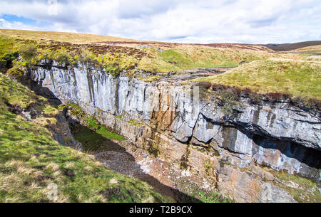 Ein grosser Felsen Schlucht mit massiven Klippen in einer kargen, grünen Landschaft in der Nähe der Gipfel des Pen-y-Gent im Peak District, England. Stockfoto