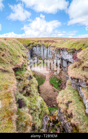 Ein grosser Felsen Schlucht mit massiven Klippen in einer kargen, grünen Landschaft in der Nähe von Peak der Pen-y-Gent im Peak District, England. Stockfoto