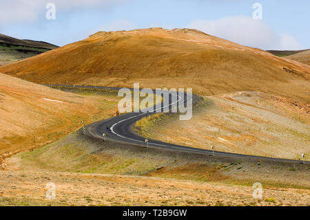 Kurvige Straße in Island zwischen felsigen Feldern. Stockfoto