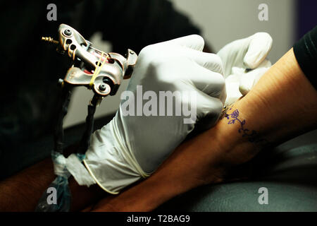 Mann in weißen Handschuhen, die Tätowierung auf der Frau arm, Maharashtra, Indien. Stockfoto