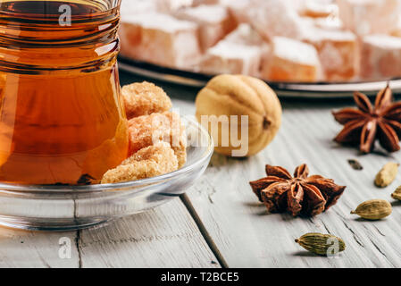 Tee in arabischen Glas mit Turkish Delight Rahat Lokum und verschiedene Gewürze über Holz- Oberfläche Stockfoto