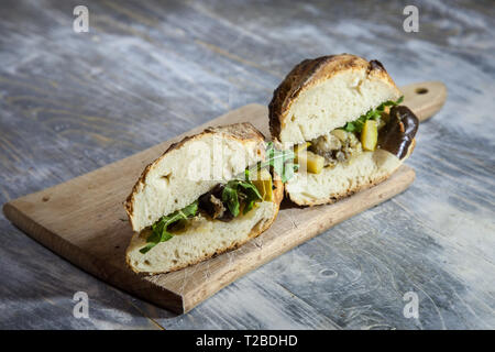 Pflanzliche sanwdich in einem Baguette, aus Zucchini und Auberginen auf Anzeige auf einem rustikalen Holztisch, Schnitt in zwei Bild eines typischen vegetabl Stockfoto