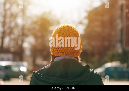 Ansicht der Rückseite des casual weibliche Person zu Fuß auf der Straße im sonnigen Frühling Morgen Stockfoto