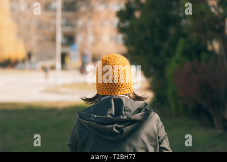 Ansicht der Rückseite des casual weibliche Person zu Fuß auf der Straße im sonnigen Frühling Morgen Stockfoto