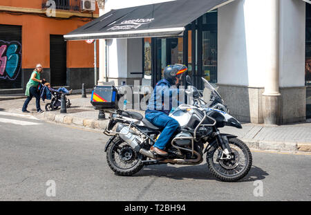 Frau treibt ein Kinderwagen und ein Mann auf einem Motorrad Stockfoto