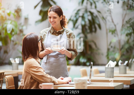 Attraktive Kellnerin Kaffee zu Gast. Stockfoto