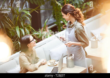 Kellnerin im Gespräch mit jungen Kunden im Cafe Stockfoto