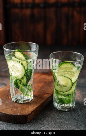 Gurke und Basilikum infundiert Wasser in zwei Gläser auf rustikalen Hintergrund Stockfoto