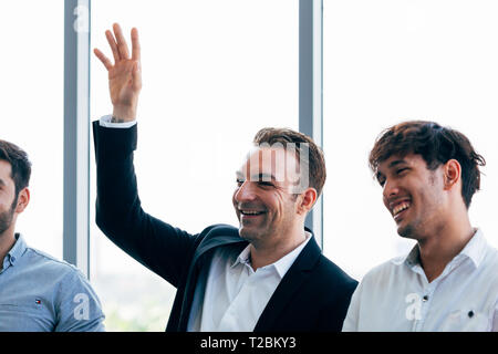 Close-up Senior kaukasischen Geschäftsmann heben die Hand nach oben neben mit den Kollegen im Seminar Diskussion Stockfoto