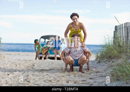 Porträt von einem jungen Paar, das Spaß am Strand mit Freunden. Stockfoto