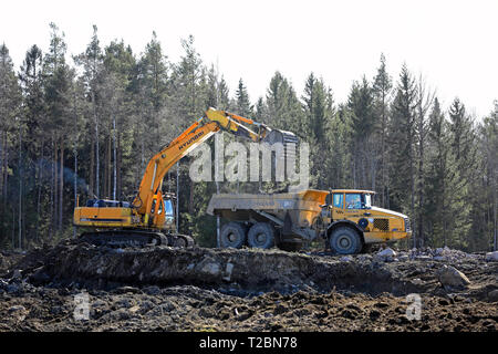 Lieto, Finnland - 22. März 2019: Hyundai Robex450LC Bagger lasten Volvo A35 D Verkehrsunternehmer auf einer Baustelle in Finnland am Tag des Frühlings artikuliert Stockfoto