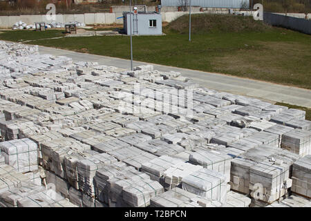 Viele Pakete von Porenbeton auf Paletten, der eine auf dieser, der andere auf einem im Werks- und Lagergebäude. Blick von oben auf den industriellen Bereich. Stockfoto