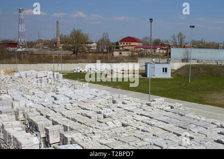 Viele Pakete von Porenbeton auf Paletten, der eine auf dieser, der andere auf einem im Werks- und Lagergebäude. Blick von oben auf den industriellen Bereich. Stockfoto