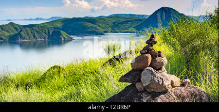 Steine Turm, Rock zen Skulptur in der Natur und Harmonie Landschaft mit grünen Hügeln der Insel Padar im Komodo National Park. Stockfoto