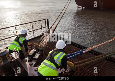 Port Operations für den Transport von Eisenerz. Dolphin Anlegestelle Anlegestelle mit rigger mit Quick release Seil Haken als Schiff setzt Segel Stockfoto