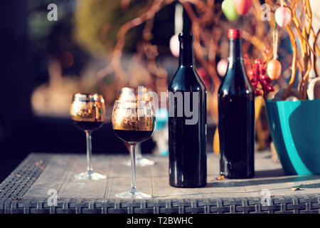 Flasche Wein, Glas und Ostereier im verschwommenen Hintergrund. Frühling Ostern Konzept. Stockfoto