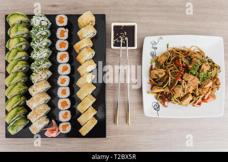 Sushi Rollen mit yakisoba und Sojasauce auf einem Holztisch Stockfoto