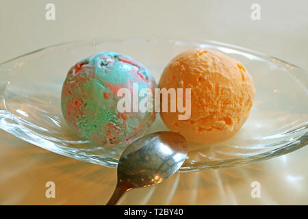Schaufeln von Pastell Color Bubble Gum Eis und Orangen Eis in einem Glasgefäß Stockfoto