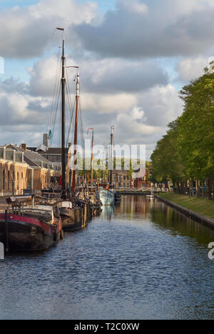 Einen Kanal Szene mit historischen Schiffen aus Holz günstig und gut gepflegten Rasen Banken an einem Kanal in Den Helder in den Niederlanden. Stockfoto