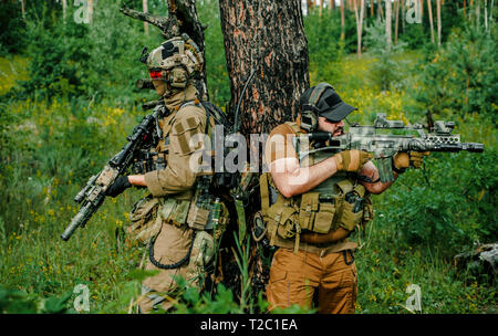 Airsoft Männer mit Gewehren stehen Rücken an Rücken. Soldaten stand auf einem Hügel und auf Abruf im Wald Stockfoto