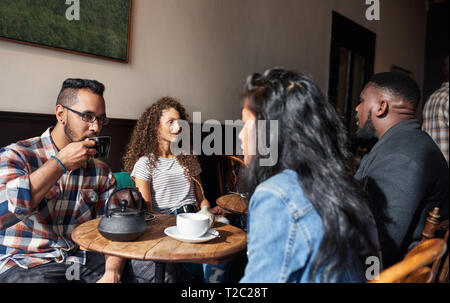 Vielfältige Gruppe von jungen Freunde sitzen an den Tischen in einem angesagten Café Kaffee trinken und reden Stockfoto