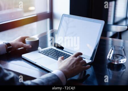 Junger Mann bei der Arbeit auf seinem Laptop in einem Café, Rückansicht der Geschäftsmann Hände beschäftigt mit Laptop im Büro Schreibtisch Stockfoto