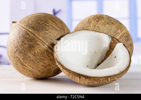 Gruppe von zwei ganze Hälfte der frischen bio Kokosnuss mit blauen Fenster in einem weißen Küche Stockfoto