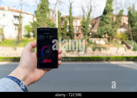 Home Automation und Smart Home Konzept. Die nad-Holding ein Smartphone auf der Straße und die Einstellung der Home Temperatur aus einer App. Stockfoto