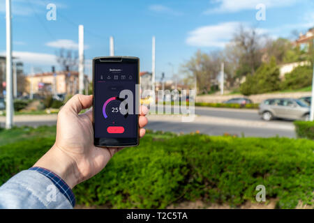 Home Automation und Smart Home Konzept. Die nad-Holding ein Smartphone auf der Straße und die Einstellung der Home Temperatur aus einer App. Stockfoto