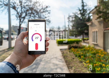 Home Automation und Smart Home Konzept. Die nad-Holding ein Smartphone auf der Straße und die Einstellung der Home Temperatur aus einer App. Stockfoto