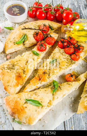 Traditionelle hausgemachte italienische Fladenbrot Focaccia. Focaccia mit Tomaten und Basilikum, Holz- Hintergrund, Ansicht von oben Stockfoto