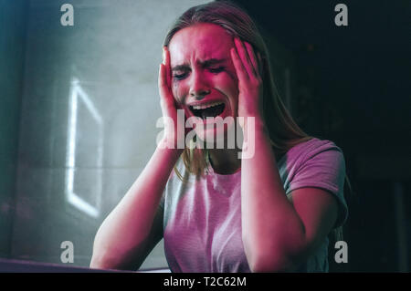 Mit Drogensucht kämpfen. Drogenabhängig hält Hände in die Hand und ist verrückt in der Nähe von Drogen. Drogenabhängige Frau mit Verschmiertem Make-up in Schreien Stockfoto